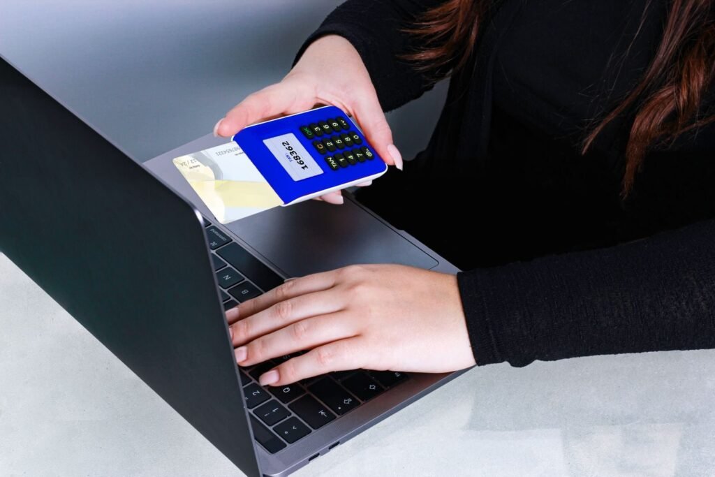Person using card reader and laptop for secure online payment, showcasing modern cashless technology.
