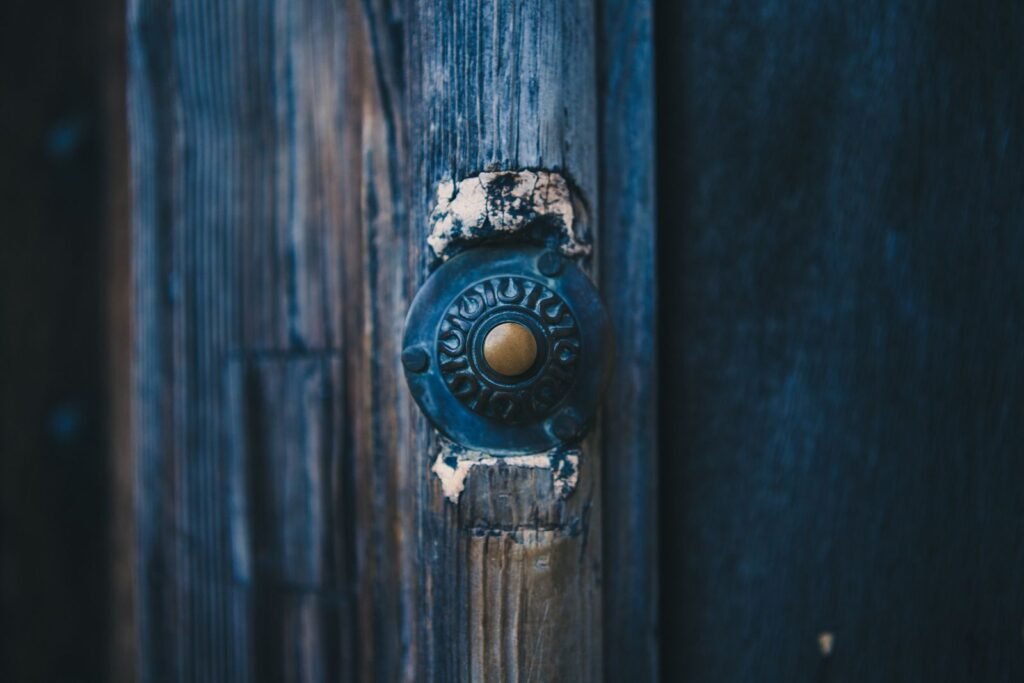 Close-up of an antique doorbell on a rustic wooden door, vintage style.