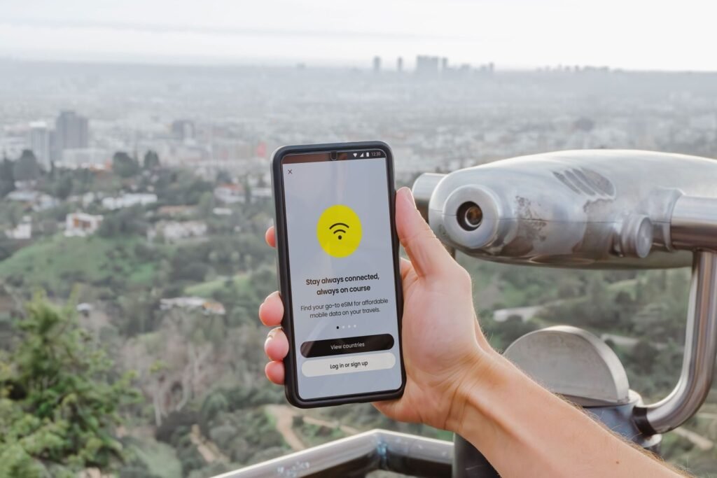 Photo by Jacob Smartphone displaying connectivity app with Los Angeles cityscape in the background.
