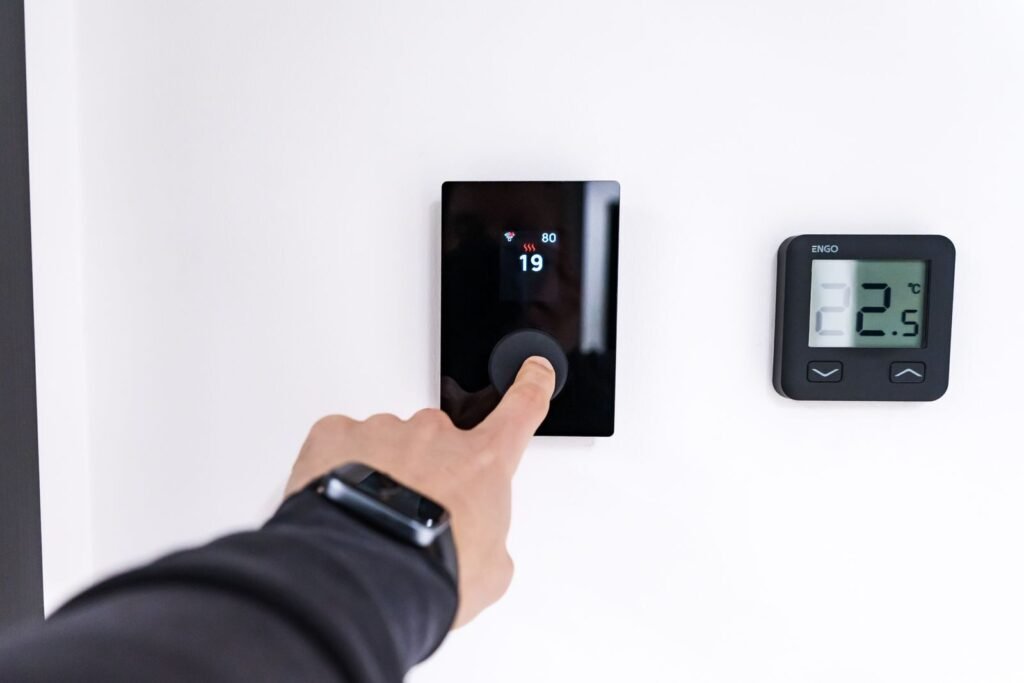 Photo by HUUM │sauna heaters A hand adjusting a digital thermostat in a modern home interior, showcasing smart home technology.