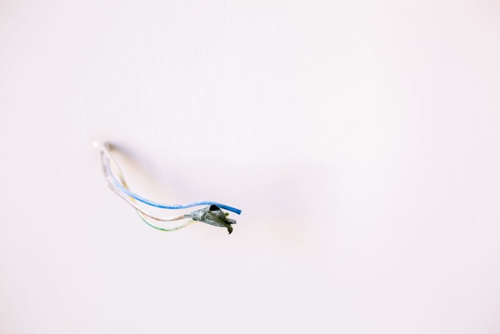 Photo by La Miko Loose electrical wires protruding from a white wall, ideal for home improvement concepts.