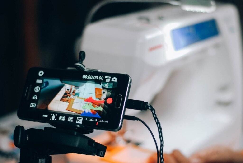 Photo by rakhmat suwandi Smartphone capturing sewing machine process, perfect for DIY and crafting content.