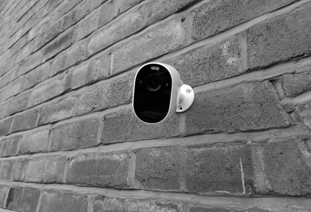 Photo by Please donation Close-up of a security camera mounted on a brick wall in monochrome.